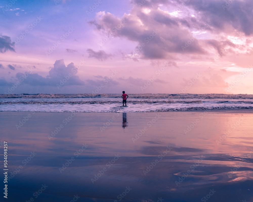 Fototapeta premium child enjoying the waves in the beach during sunset.