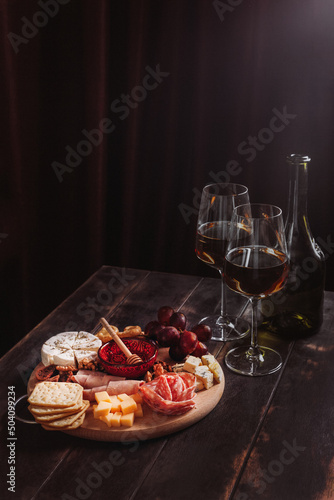 Fototapeta Naklejka Na Ścianę i Meble -  Wine appetizer. Sausage and cheese cut with fruit, cookies and sauce with two glasses of white port and a bottle