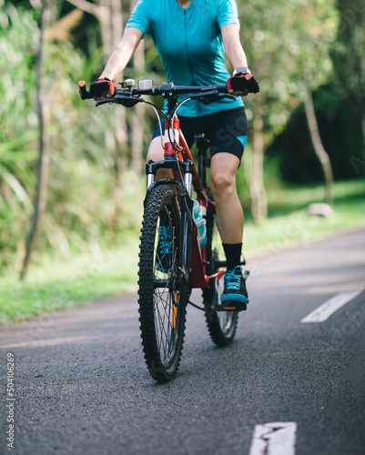 Woman cycling on tropical park trail in summer © lzf