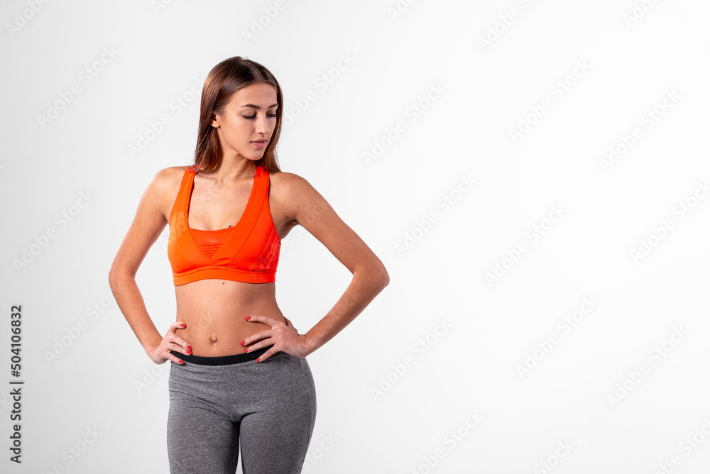girl in a bright sports top, hands on hips on a white background. healthy lifestyle concept. girl in a bright sports top, hands on hips on a white background. healthy lifestyle concept.