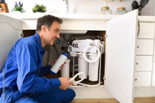 Foto Technician installing reverse osmosis equipment under the sink