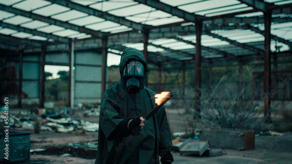 Soldier man with gas mask in a destroyed building by war with torch