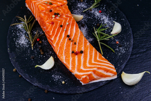 Raw salmon fillet with spices on black slate