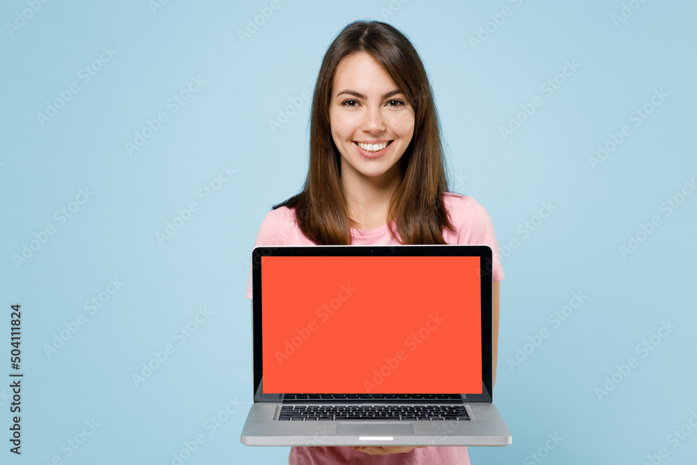 Naklejka premium Young smiling freelancer happy caucasian woman 20s in pink t-shirt hold use work on laptop pc computer with blank screen workspace area isolated on pastel plain light blue background studio portrait
