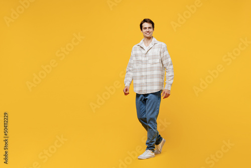 Full body young smiling happy cheerful caucasian man 20s wearing white casual shirt walking going strolling look camera isolated on plain yellow background studio portrait. People lifestyle concept.