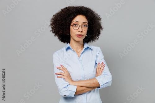 Young serious employee business corporate lawyer woman of African American ethnicity in classic formal shirt work in office hold hands crossed folded look camera isolated on grey background studio