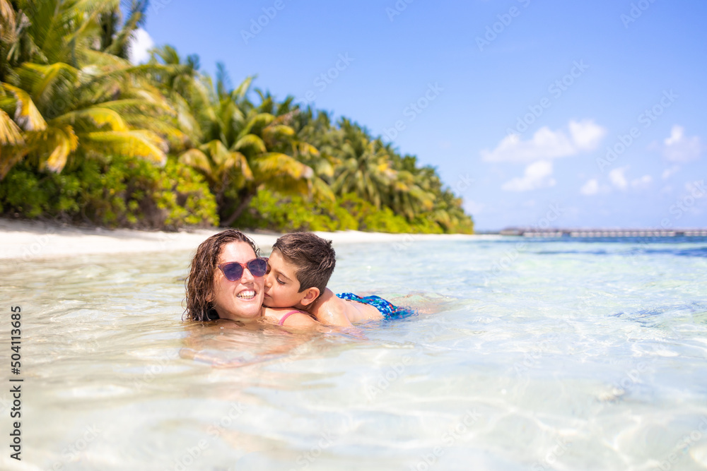 Mother and son in the water on a beach in the Maldives