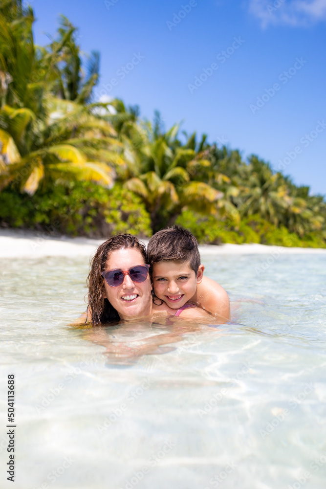 Obraz premium Mother and son in the water on a beach in the Maldives