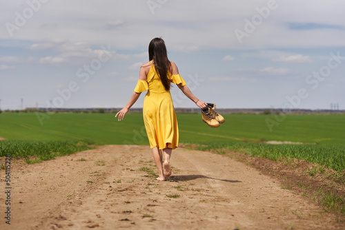 Young woman on a dirt road, barefoot