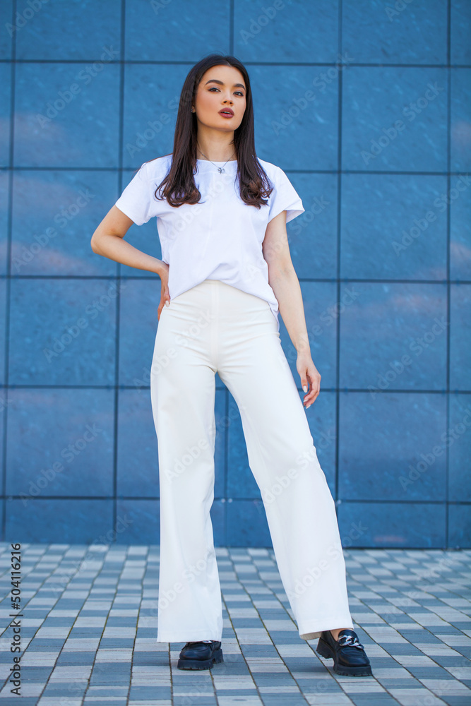 Portrait of a young beautiful brunette woman in white trousers Portrait of a young beautiful brunette woman in white trousers