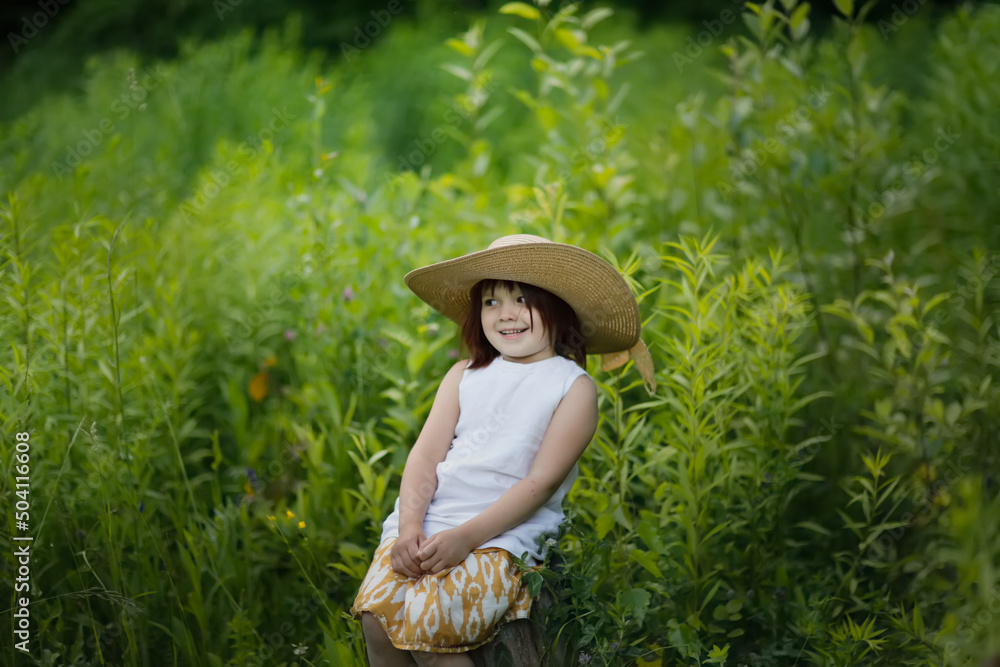 Obraz premium Cute kid girl playing in grass in park, child among vegetation in forest