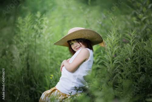 Cute kid girl playing in grass in park, child among vegetation in forest