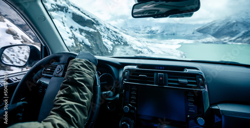 Driving off road car on snowing high altitude mountain trail on winter day . photo