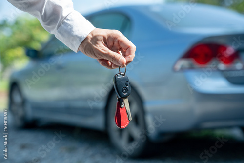 selling car, car sale, deal concept The dealer gives the car keys to the new owner or renter with an insurance contract.