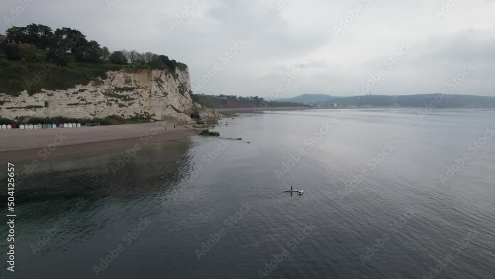 Paddle boarders Beer fishing village and beach Devon England drone aerial view Paddle boarders Beer fishing village and beach Devon England drone aerial view