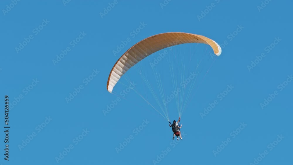 Parachutist jumps with instructor. Paragliders, fearless skydivers tandem flying against clear blue sky. Extreme parachute sport, lifestyle, hobby, adventure. Skydiving, summer activity Parachutist jumps with instructor. Paragliders, fearless skydivers tandem flying against clear blue sky. Extreme parachute sport, lifestyle, hobby, adventure. Skydiving, summer activity