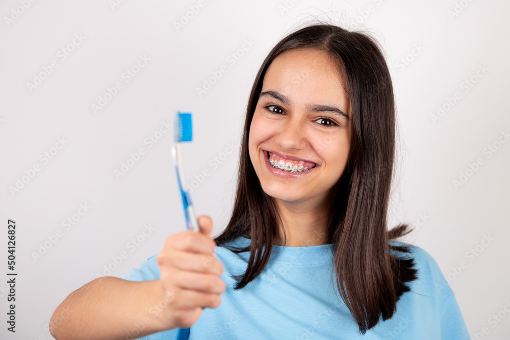 Portrait of a happy teen girl with braces holding a toothbrush smiling. Portrait of a happy teen girl with braces holding a toothbrush smiling.