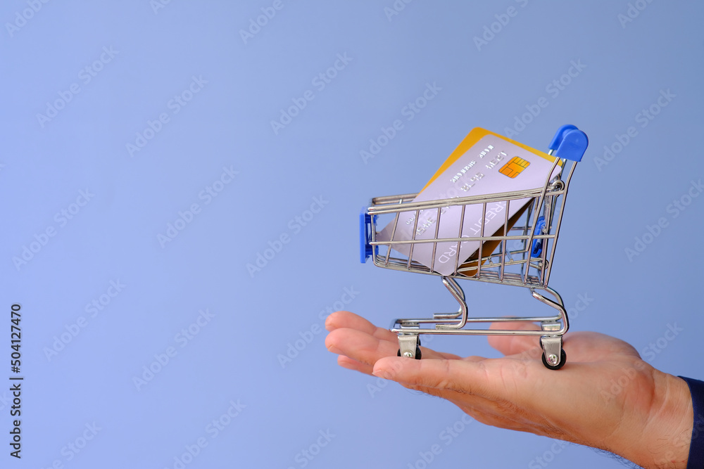 Hand holds a credit card and is engaged in online shopping, e-commerce, internet banking, and money expenditure. Hand holds a credit card and is engaged in online shopping, e-commerce, internet banking, and money expenditure.