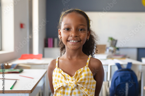 Portrait of smiling african american elementary schoolgirl standing in classroom