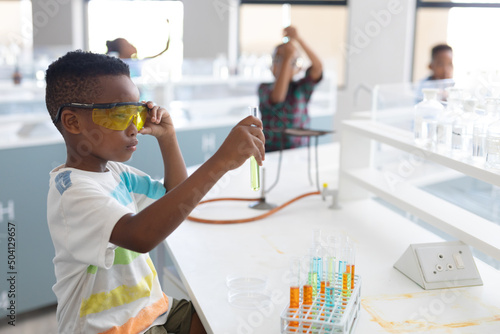 African american elementary schoolboy performing chemical experiment during chemistry class