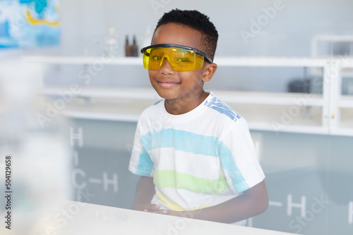Portrait of african american elementary schoolboy wearing protective eyewear during chemistry class