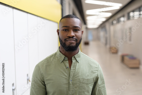 Portrait of confident african american young male teacher standing in school corridor