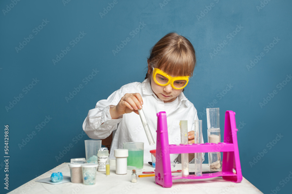 Little child student doing a chemical experiment and holding flask in hand in science class. Education and science concept Little child student doing a chemical experiment and holding flask in hand in science class. Education and science concept