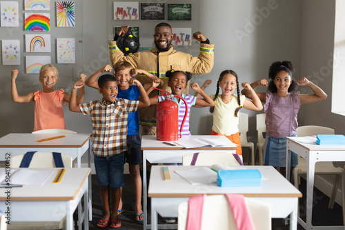 Multiracial elementary students and african american young male teacher flexing muscles