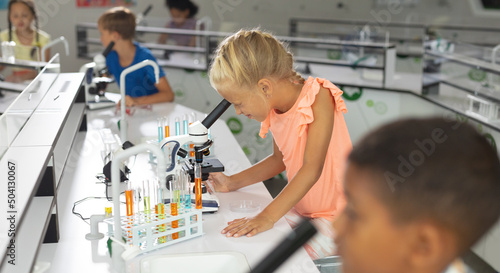 Multiracial elementary students looking through microscope during science class