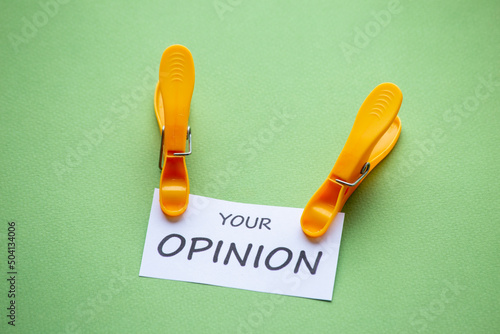 piece of paper with the phrase Tu Opinión (Your opinion) clamped on it, with a green background. concept that one should not pay too much attention to the opinion of others.