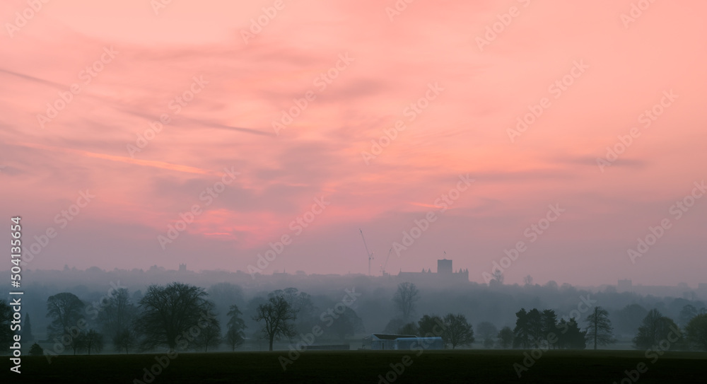 Cityscape at dawn with buildings in the sunrise on the horizon