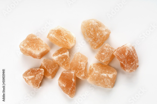 Pink stones of himalayan salt on surface, on white background close-up