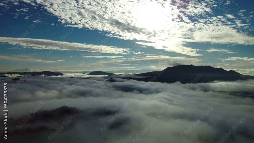 Aerial drone view above the clouds of the peaks of mountain range with blue sky Aerial drone view above the clouds of the peaks of mountain range with blue sky