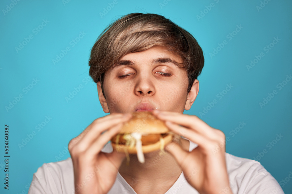 Very hungry young man holding tasty hamburger Very hungry young man holding tasty hamburger