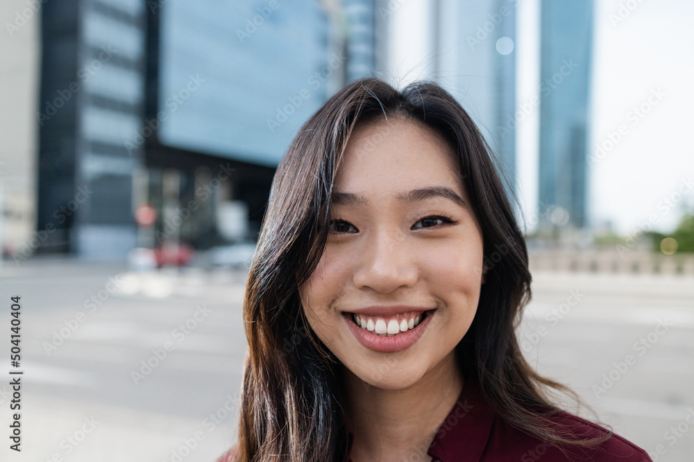 Asian business woman working outside of the office with city in background - Focus on face