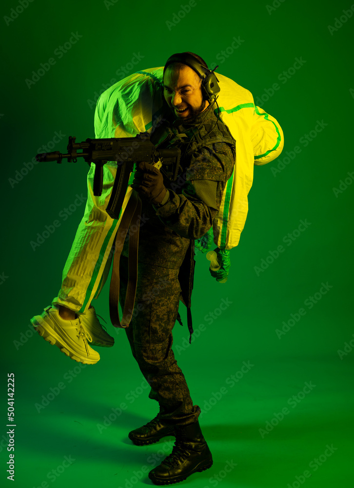 a soldier carries a medic and shoots back, shouting. Studio. green background