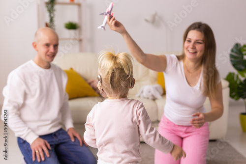 Cochlear implant on the child girl head and playing with mother and father. Hearing aid and deafness and innovative health technology concept