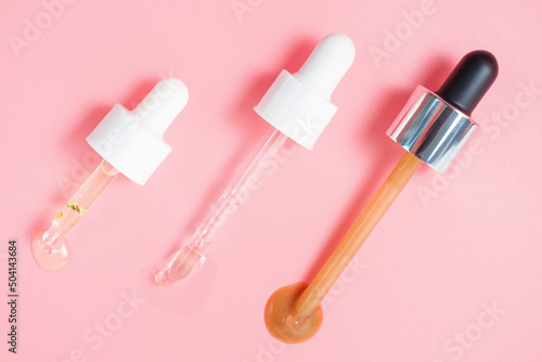 Three pipettes with serum and collagen on a pink background close-up. © TATIANA