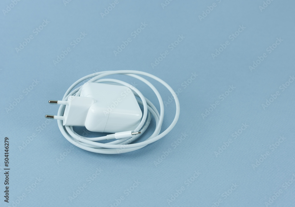 A charger for a tablet on a blue background. Phone charger. A charger for a tablet on a blue background. Phone charger.