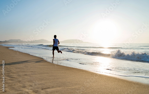 Young man running along beach  in the morning