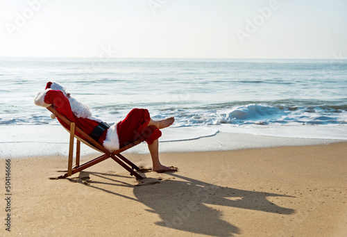 Bild auf Leinwand Christmas santa claus lying on a beach chair.