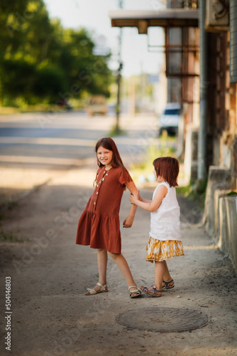 Summer time, Cute girls sisters in dresses walk around the city, summer walks and happy childhood © natalialeb