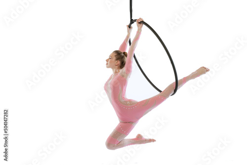 Portrait of young sportive girl, air gymnast performing on hoop isolated over white studio background. Flying high