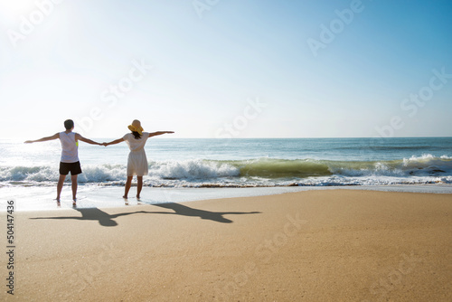 Young couple embracing enjoying ocean on beach.