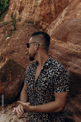 Zdjęcie lookbook, moda letnie męska, mężczyzna model w koszuli na tle skał.