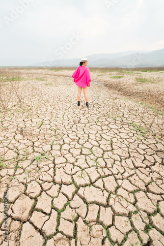 woman walking in dryland with drought ground texture. concept climate changed.