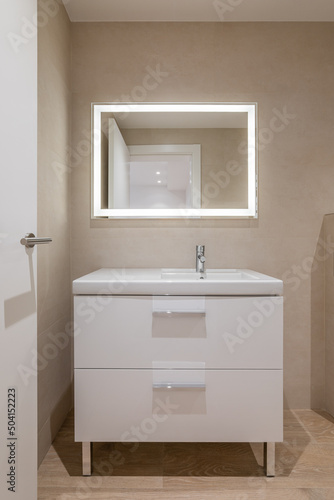 Modern bathroom with beige tiles, furniture and rectangular large mirror with lighting