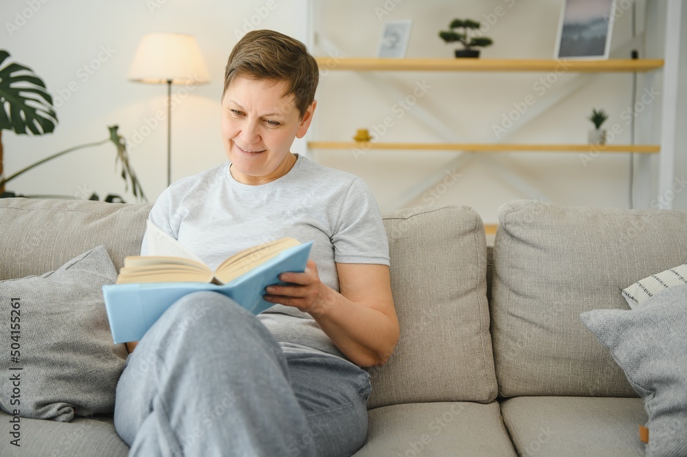 woman in home sitting on sofa reading book. woman in home sitting on sofa reading book.