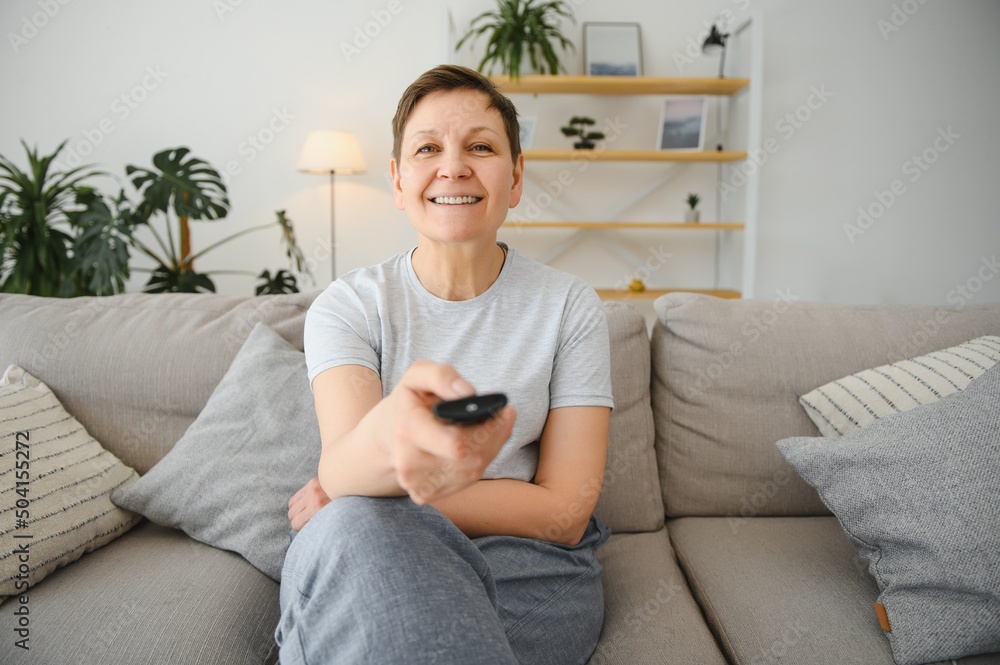 Portrait of happy older woman changing channel on television. Portrait of happy older woman changing channel on television.