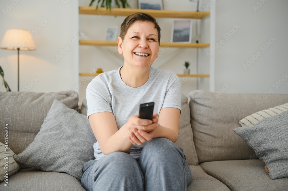 Portrait of happy older woman changing channel on television. Portrait of happy older woman changing channel on television.